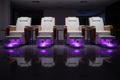 Four LIBERTÉ pedicure chairs in salon configuration with all four AURORA LED bowls glowing synchronized purple on dark floor