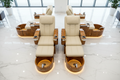Four PRIVÉ Lounge chairs fully reclined in synchronized position on white marble floor, AURORA bowls glowing warm gold, overhead 45-degree view